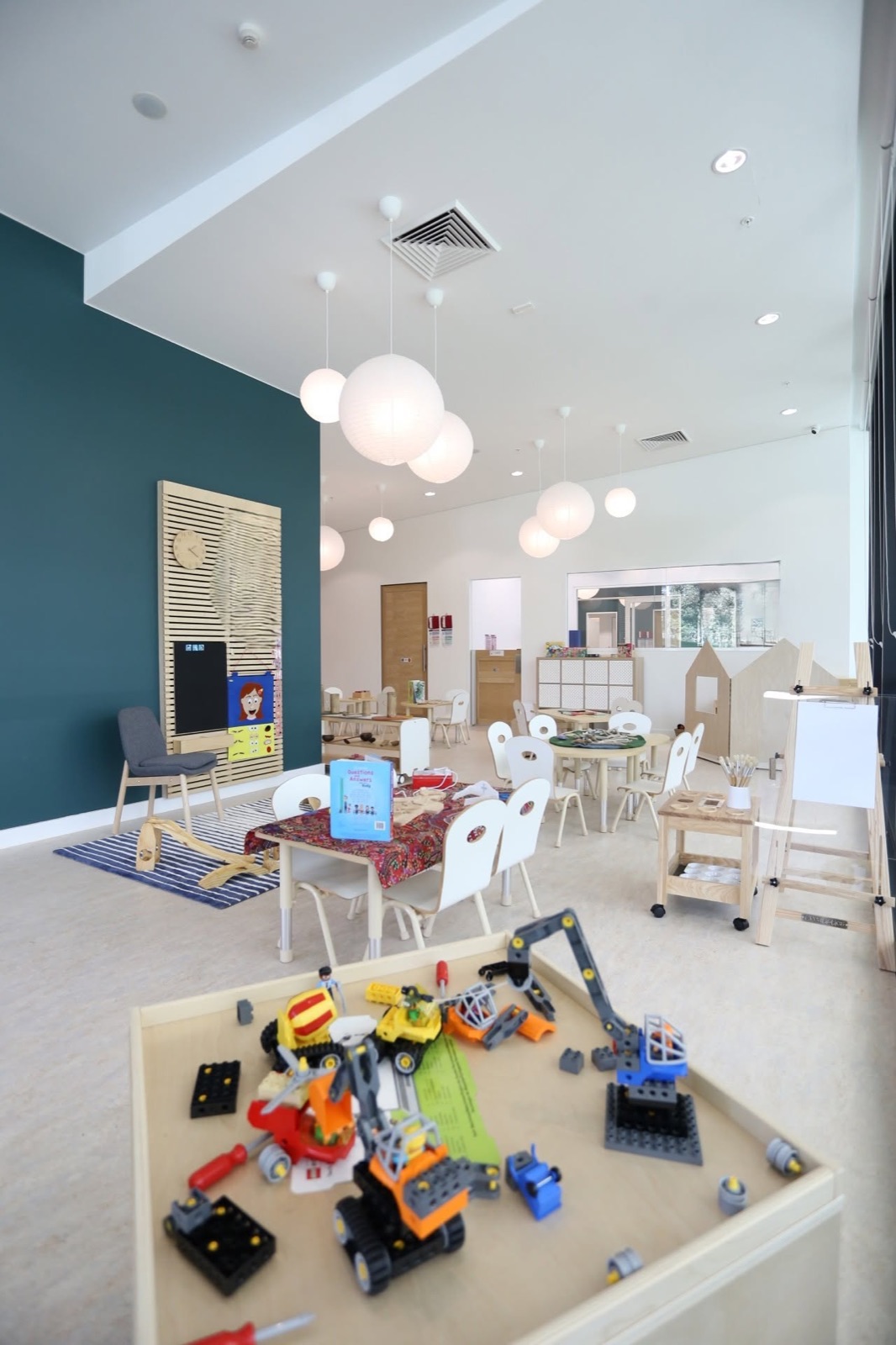 A spacious playroom with a construction table, art area and window seats